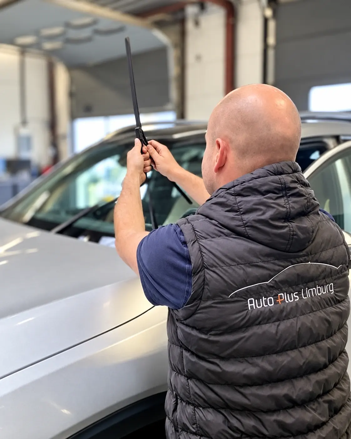 Roy werkt aan een ruitenwisser bij de voorruit van een auto